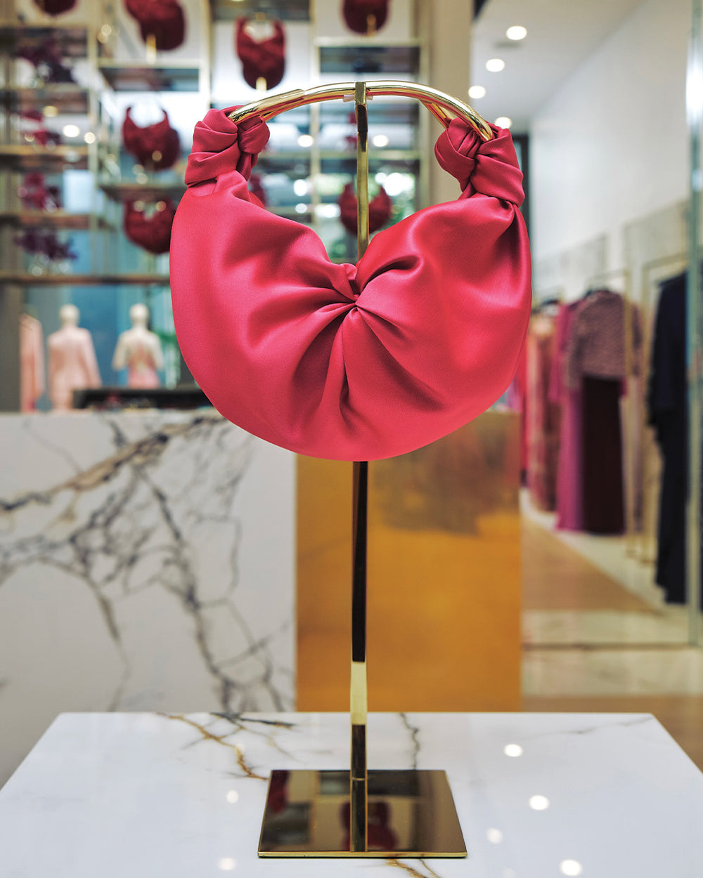 Pink headband on a gold stand with a blurred store interior in the background