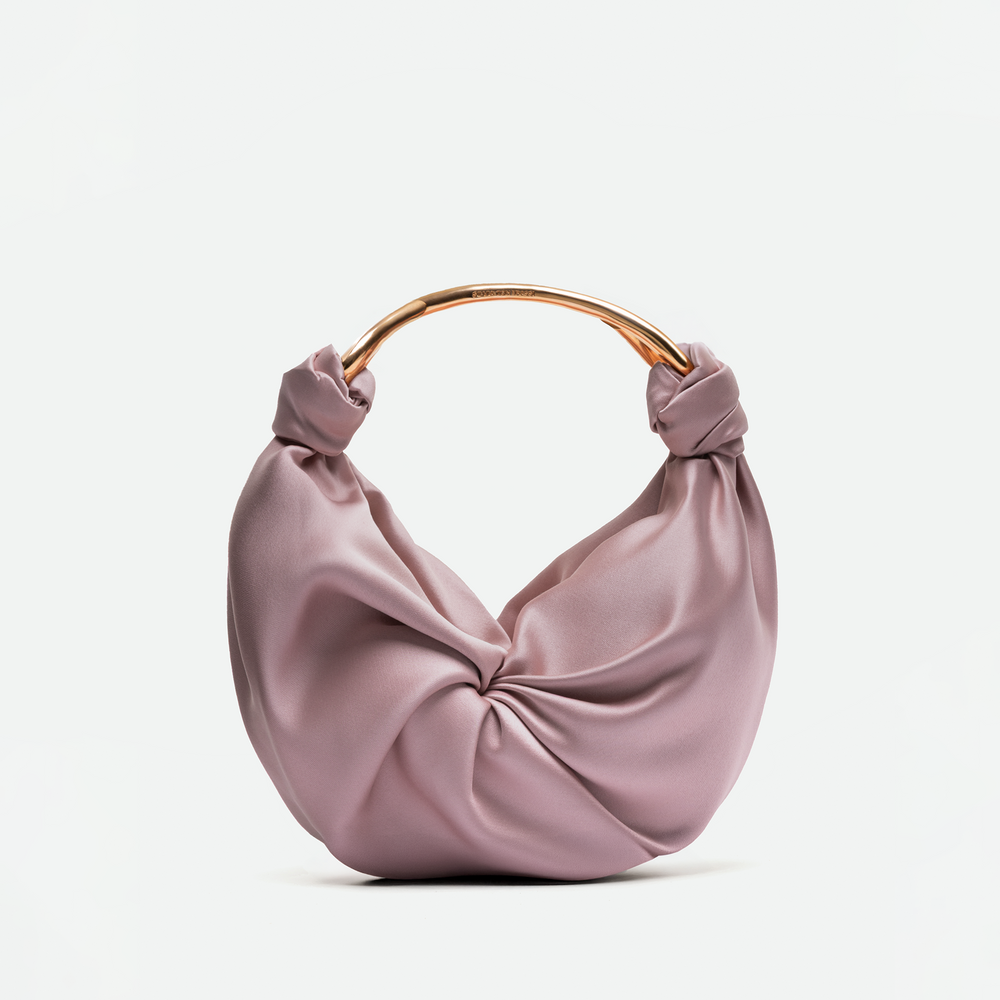 Pink handbag with a knotted design and gold handle on a white background