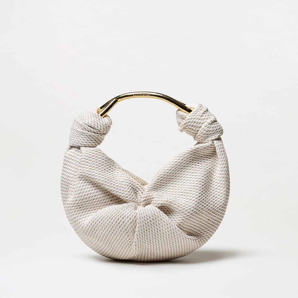 The Sofia Tennis Bag (Small) features textured cream and beige Italian fabric, a knot detail, and a gold-toned handle, shown against a plain white background.