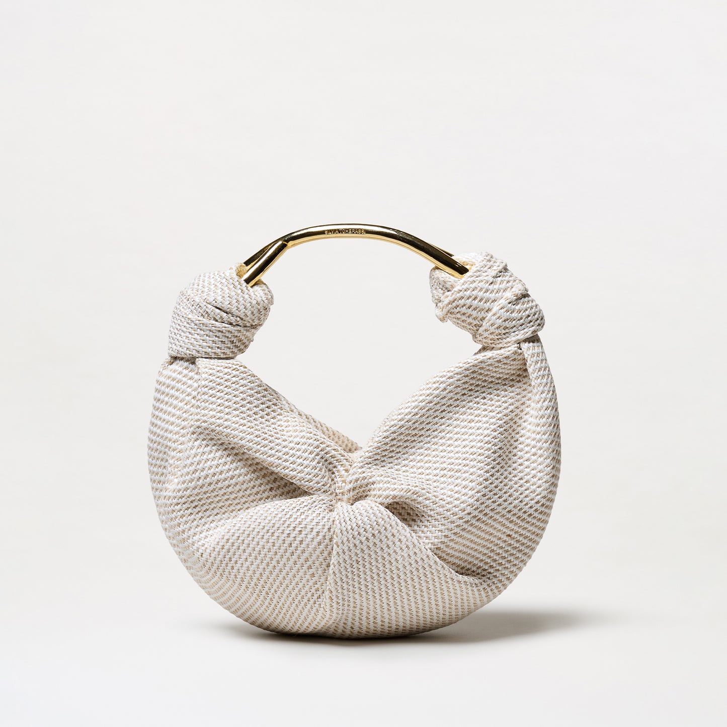 The Sofia Tennis Bag (Small) features textured cream and beige Italian fabric, a knot detail, and a gold-toned handle, shown against a plain white background.