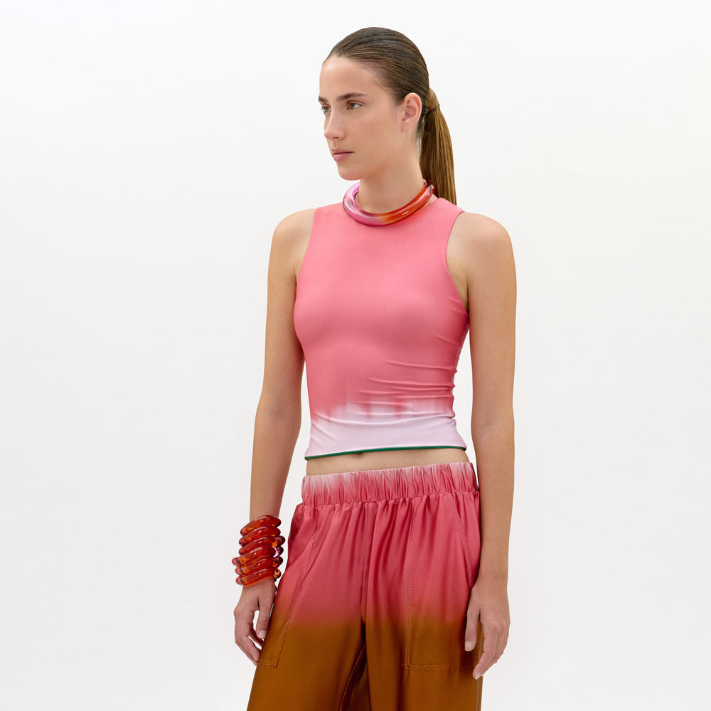 Woman wearing a pink top and brown pants on a white background