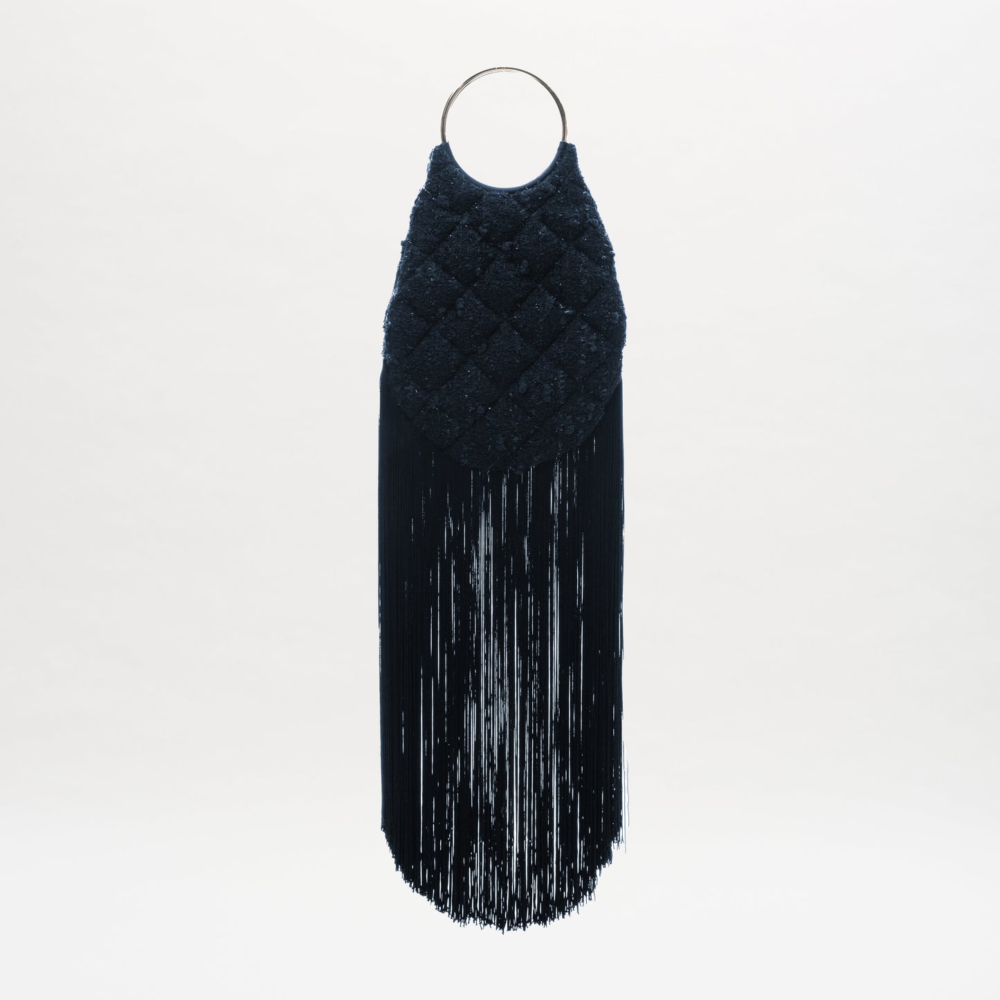 The Toblach Bag is a black, textured Jacquard bag featuring a quilted pattern, metallic top handles, and long black fringe at the bottom, shown against a white background.