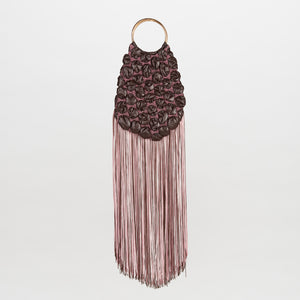 The Toblach Bag is a dark brown handbag featuring a quilted, gathered texture and long, tiered pink fringe, hanging from circular metallic handles.