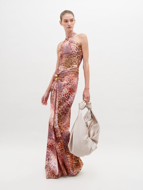 A person in a sleeveless, high-neck, colorful patterned Toyah Dress Peach Animal Print poses against a plain background, holding a large, light-colored slouchy bag. Available for pre-order now, with shipping scheduled by November 15th, 2024.