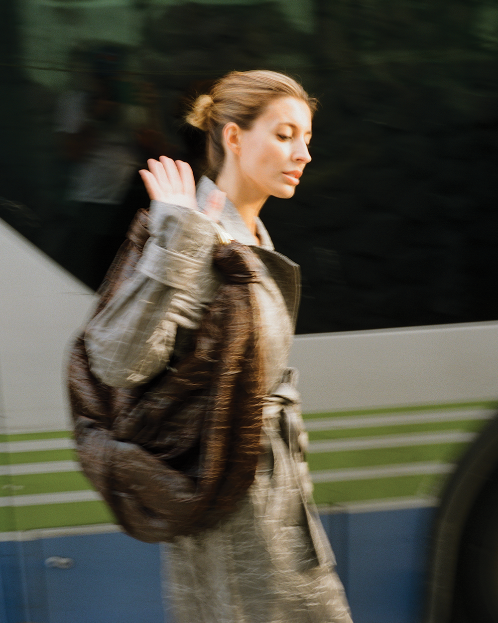 Woman in a fur coat walking past a bus