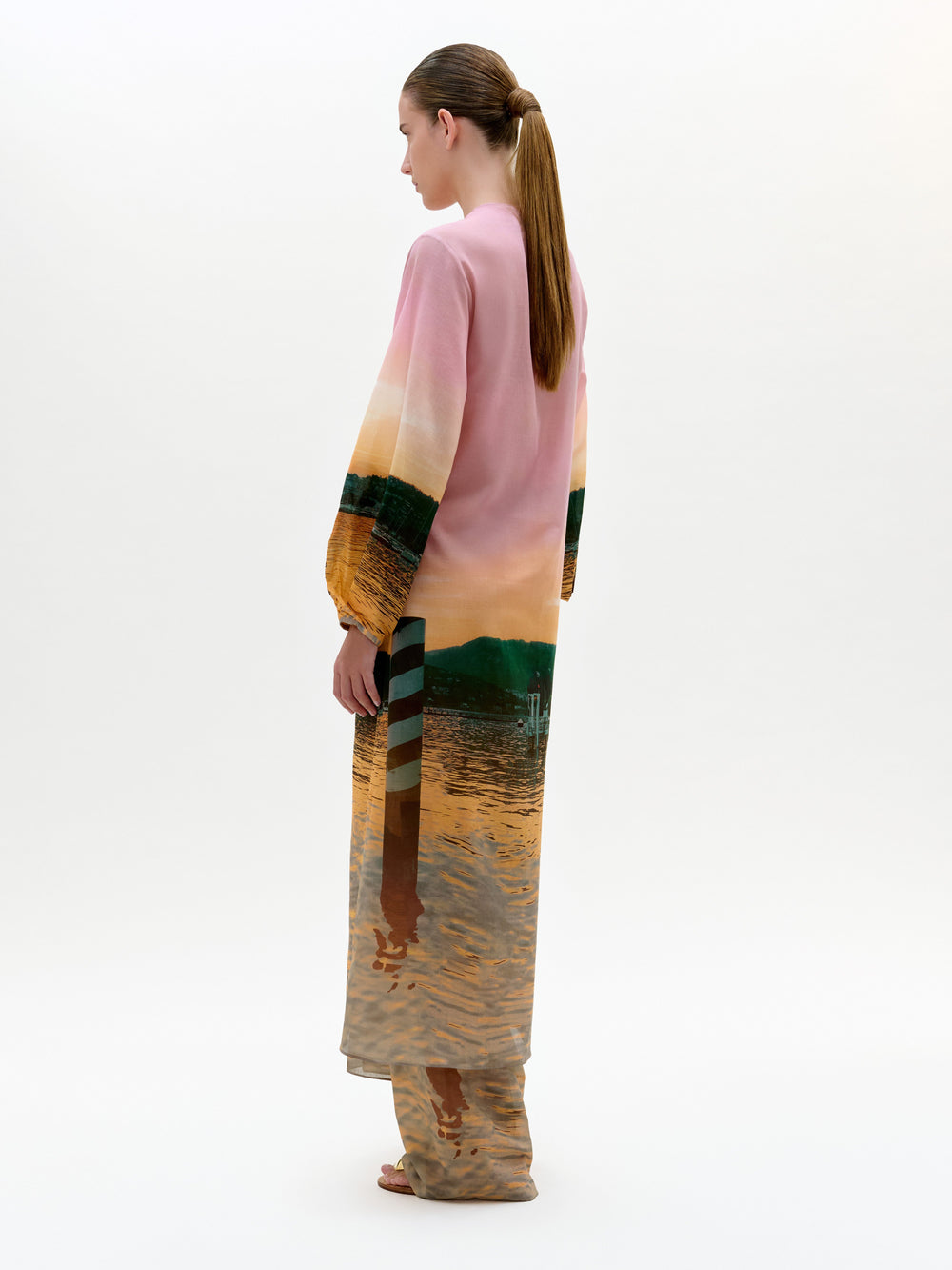 Woman wearing a long, colorful dress with a abstract pattern on a white background