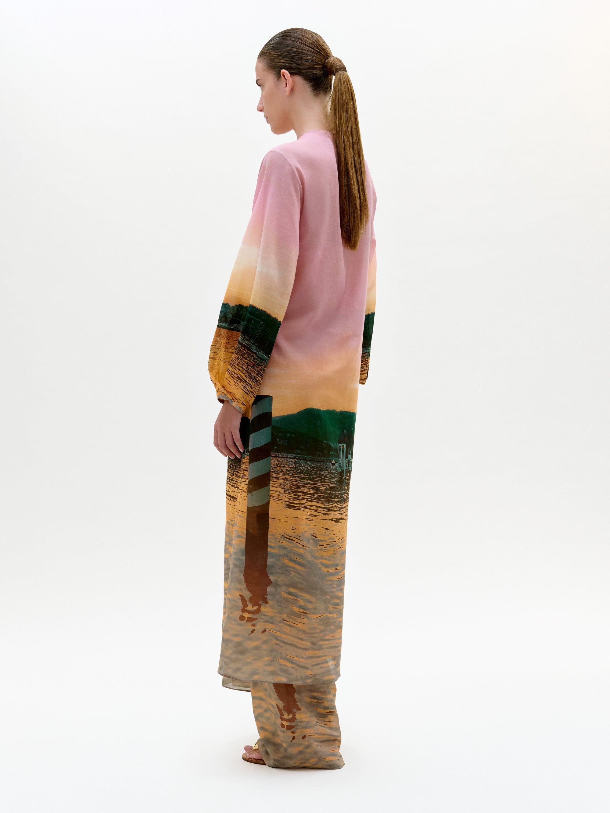 Woman wearing a long, colorful dress with a abstract pattern on a white background