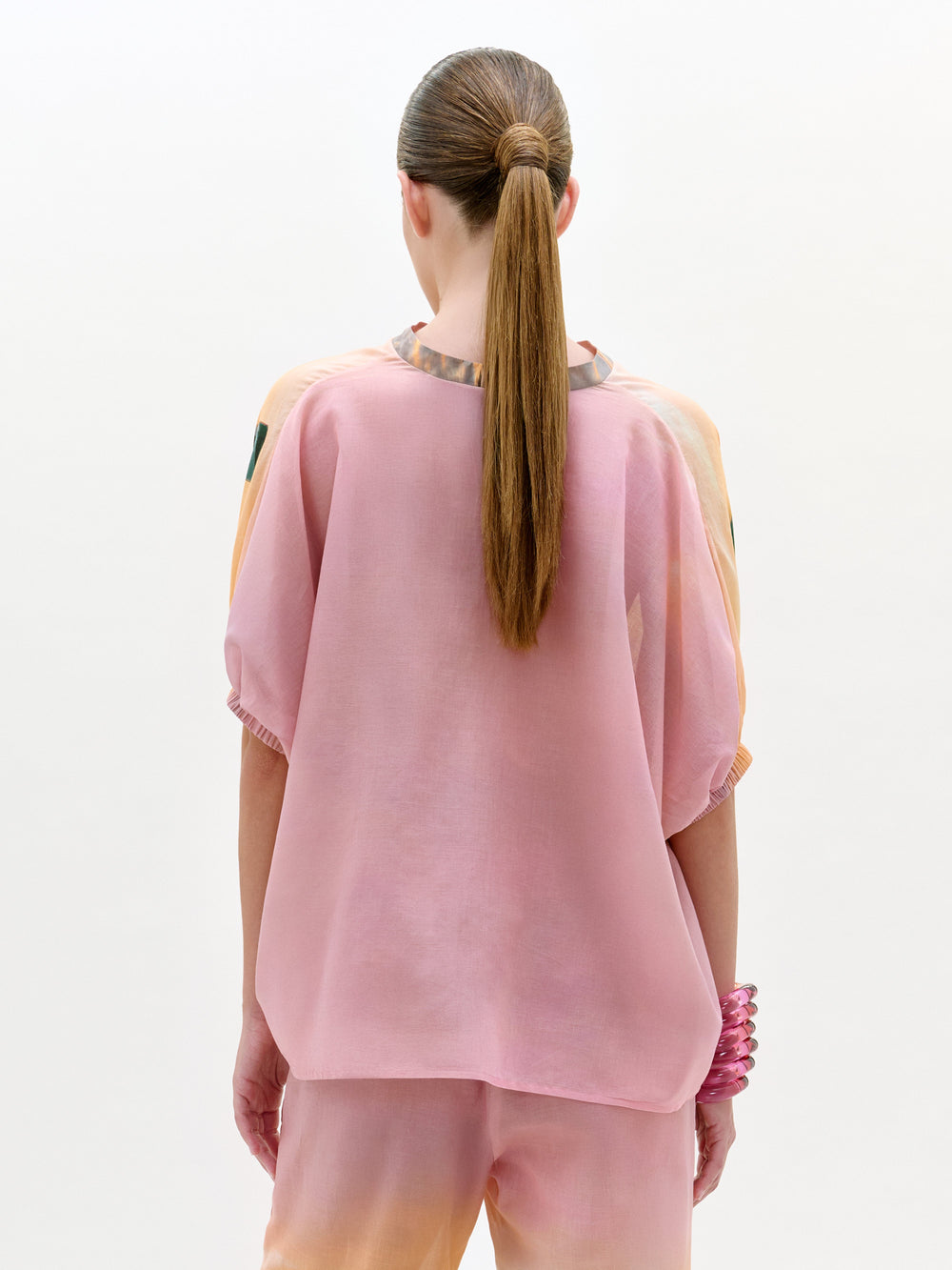Person wearing a pink outfit with a plain background