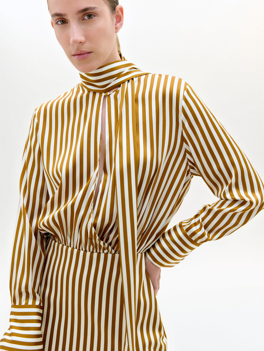 Person wearing a yellow and white striped long-sleeve top on a plain background