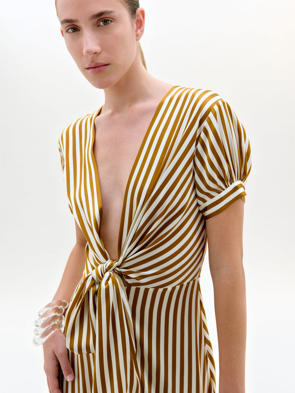 Woman wearing a yellow and white striped dress on a plain background