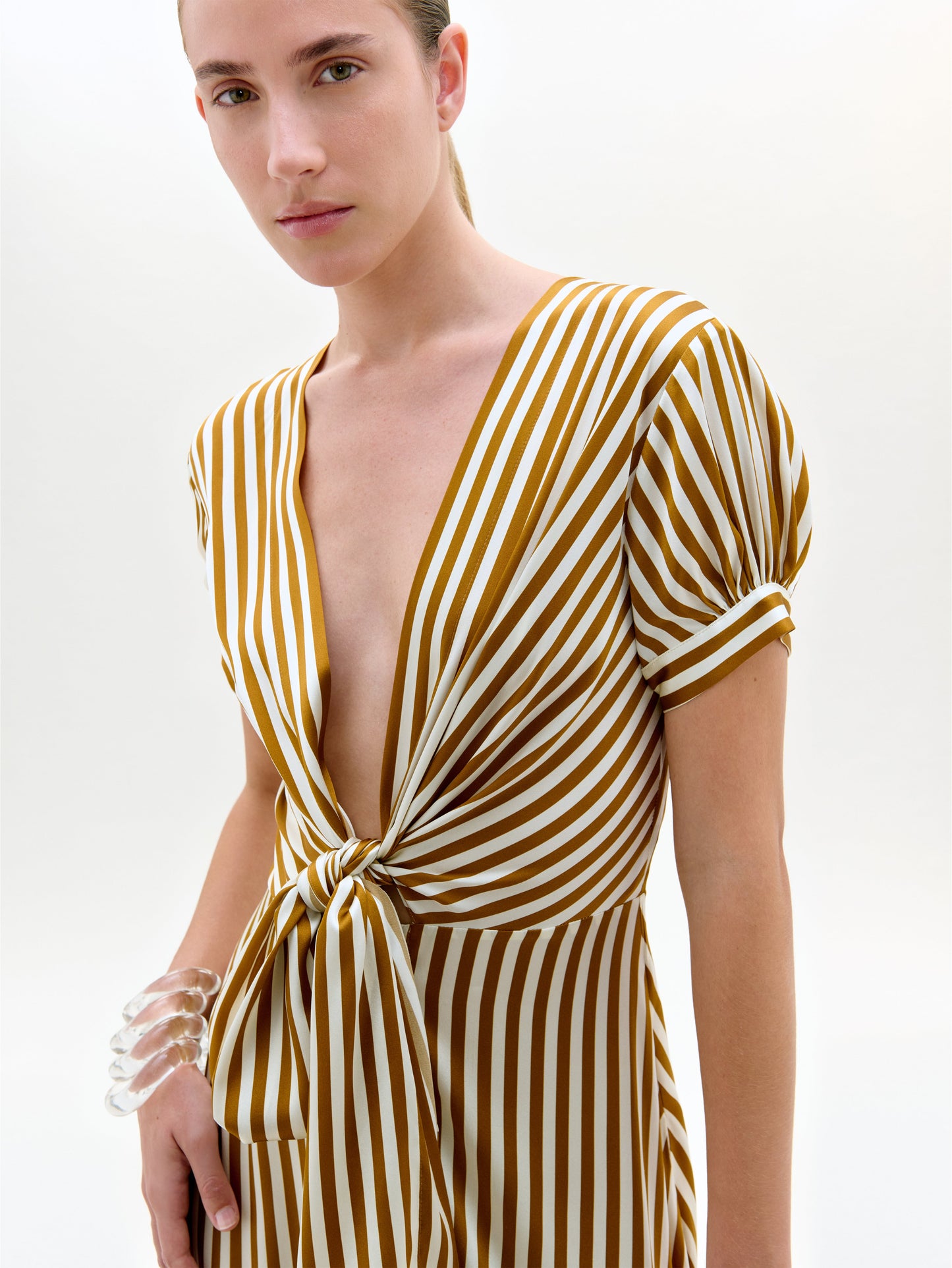 Woman wearing a yellow and white striped dress on a plain background