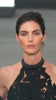 The supermodel Hillary Rhoda walking the runway wearing the Mab Dress with large black floral appliqués over sheer nude fabric, featuring Italian textile cutouts at the waist and a high neckline.