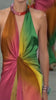 Women walking the runway wearing the Dixon Dress—a vibrant silk column gown with pink, red, orange, green, and yellow panels gathered at the waist—paired with chunky blue bracelets and a necklace.